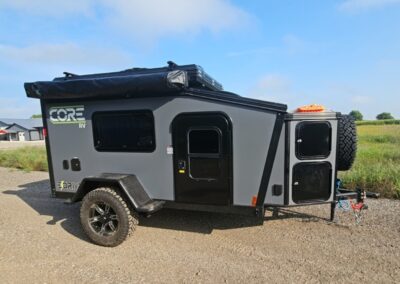 Exterior view of the CORE RV 5510 with awning, rooftop tent and front storage box