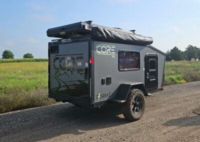 Exterior view of the CORE RV 5510 angled showing the curb size and back galley door closed with mountain graphics