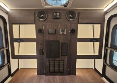 Interior view of the CORE RV 5510 front cabinet with 6 cubbies, 2 overhead cabinets, bluetooth speakers and heating vents and outlet