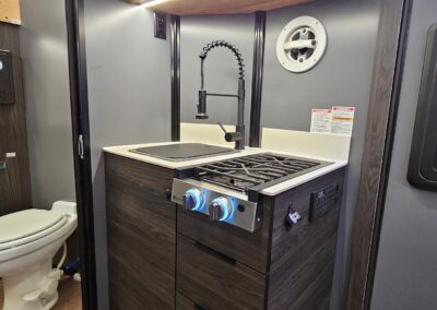 Interior view of kithenette in CORE RV including 2 burner cooktop and sink with pull out drawers