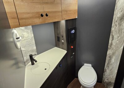 Interior view of 3/4 bath with full flushing toilet, sink, fan and upper cabinetry